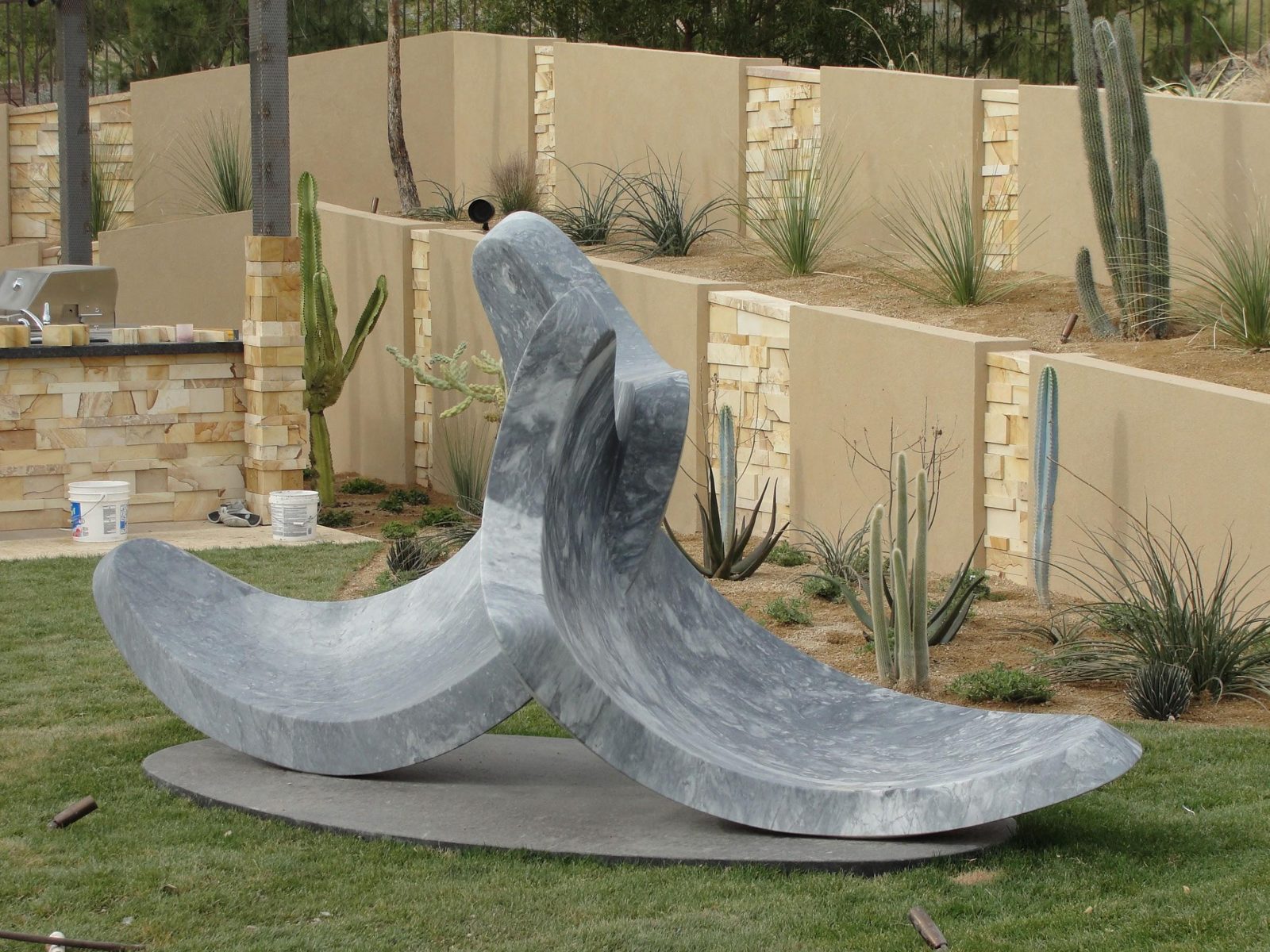 Custom-fabricated natural stone sculpture with stacked-stone accent walls in a landscaped yard
