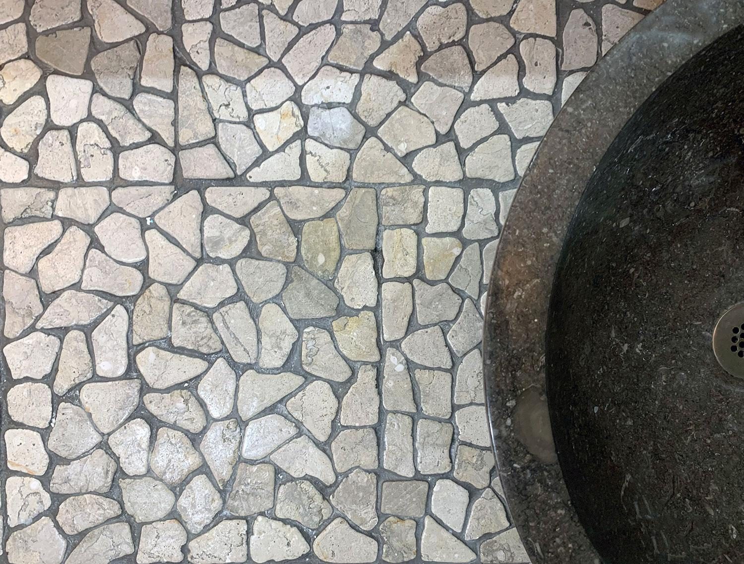 Natural stone pebble mosaic floor with a carved stone vessel sink